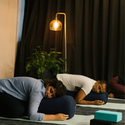 Two individuals hugging body pillows in child pose