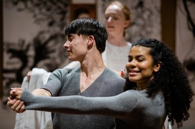 A couple in a show have their front hands stretched while their other hands are around each other's bodies